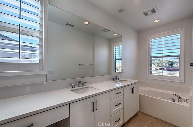 bathroom featuring tiled bath, vanity, and tile patterned floors