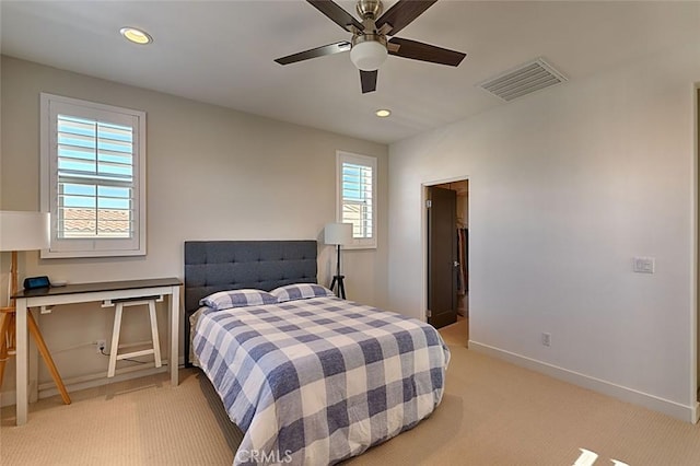 bedroom featuring ceiling fan, light colored carpet, and multiple windows