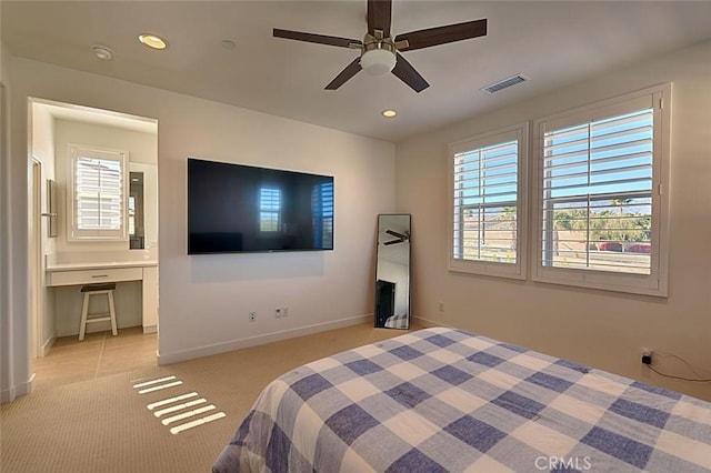 bedroom with light carpet, ceiling fan, and built in desk