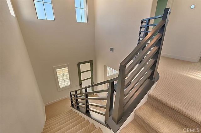 stairs featuring carpet and a towering ceiling