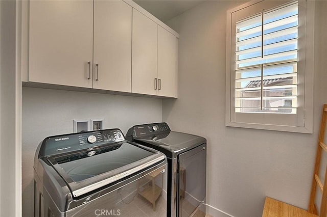 clothes washing area with cabinets and separate washer and dryer