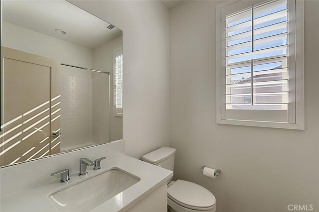 bathroom with toilet, a shower, and vanity