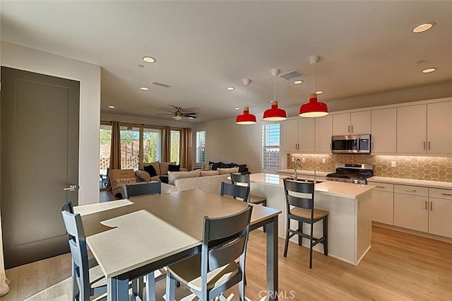 dining area featuring ceiling fan, a wealth of natural light, and light wood-type flooring