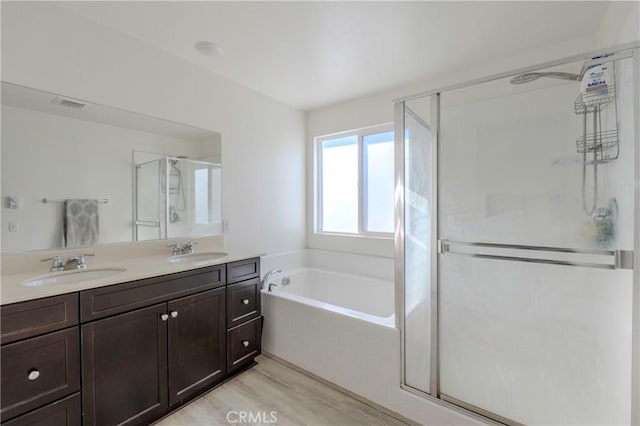 bathroom with hardwood / wood-style floors, vanity, and independent shower and bath