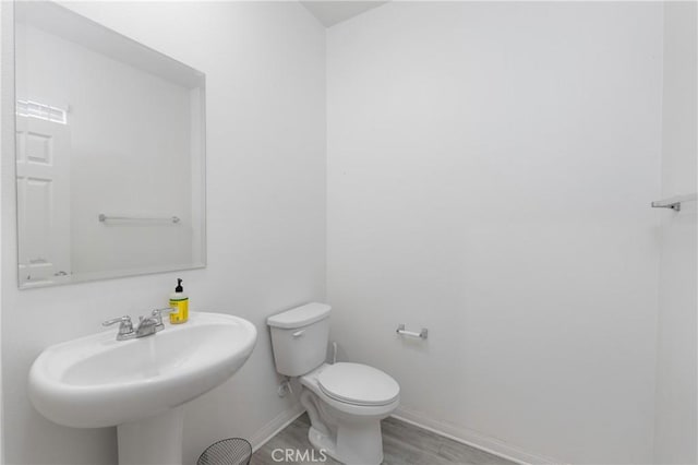 bathroom featuring toilet, wood-type flooring, and sink