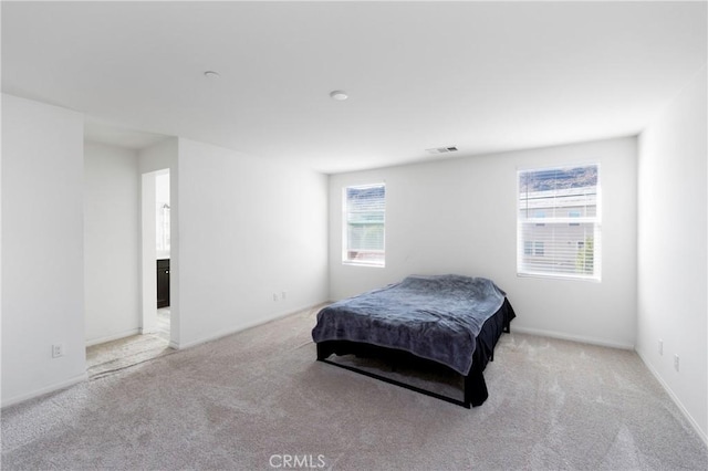 bedroom with light colored carpet and multiple windows