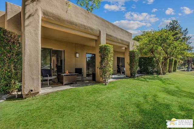 back of property featuring a fire pit, a yard, and a patio