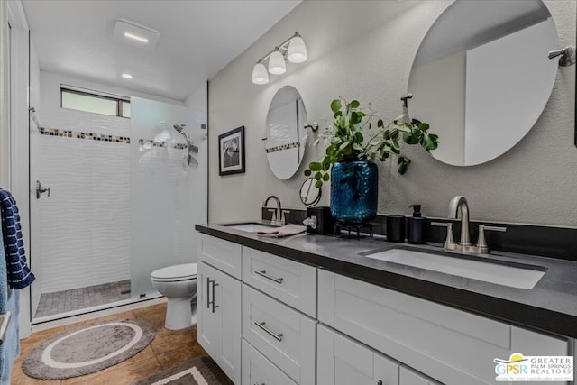 bathroom with vanity, toilet, tile patterned floors, and tiled shower