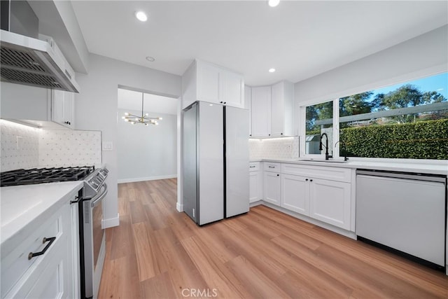 kitchen featuring appliances with stainless steel finishes, sink, wall chimney exhaust hood, and white cabinetry