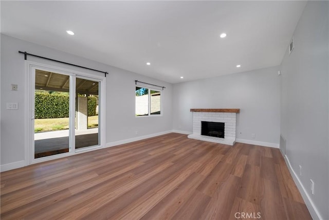 unfurnished living room with a brick fireplace and light hardwood / wood-style floors