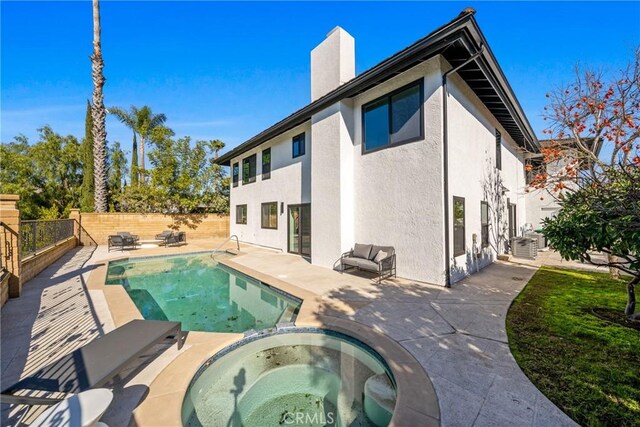 rear view of house featuring a pool with hot tub and a patio area