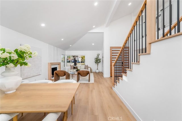 dining area featuring light wood-type flooring and lofted ceiling with beams