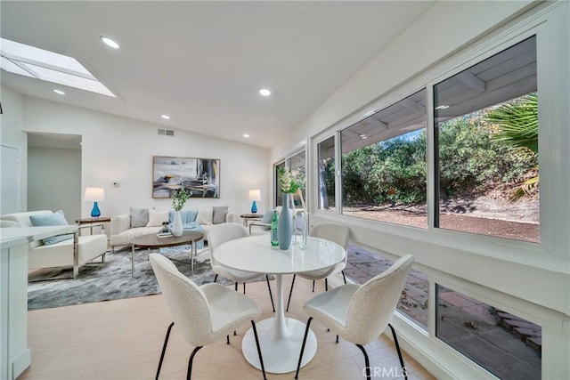 dining area with vaulted ceiling with skylight