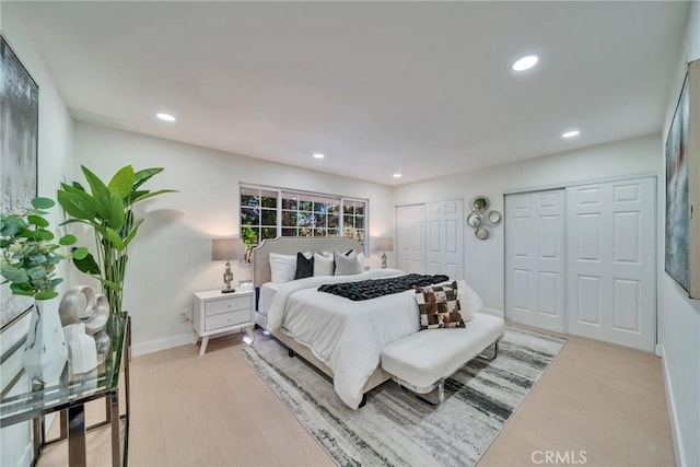 bedroom with multiple closets and light hardwood / wood-style floors