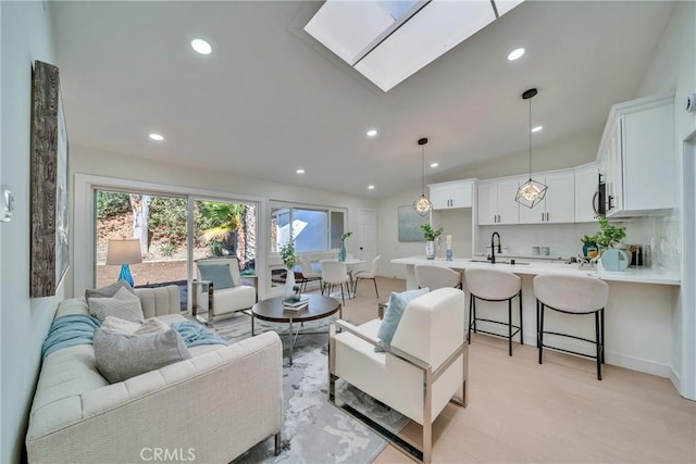 living room featuring lofted ceiling with skylight and sink