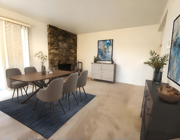 dining space featuring a stone fireplace and light colored carpet