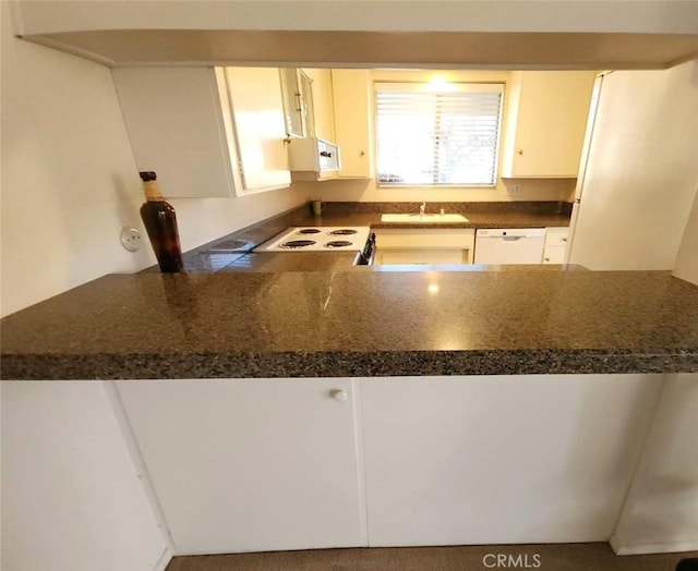 kitchen featuring range with electric cooktop, a sink, dark countertops, white cabinetry, and dishwasher