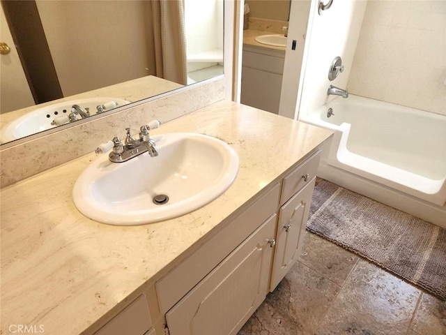 full bath featuring vanity, stone finish floor, and washtub / shower combination