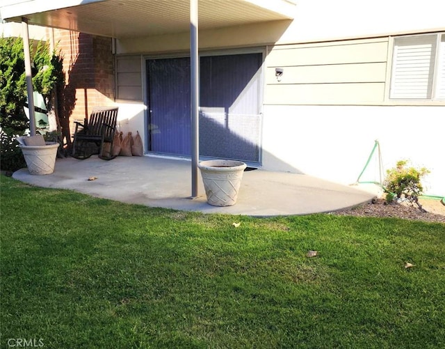 view of exterior entry with a patio and a yard