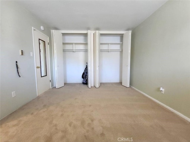 unfurnished bedroom with light colored carpet and two closets