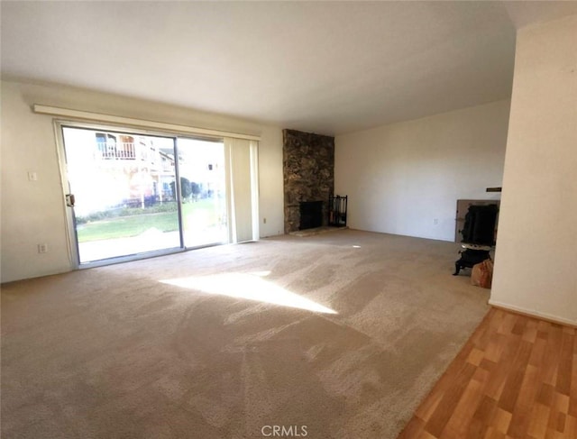 unfurnished living room featuring a stone fireplace and carpet