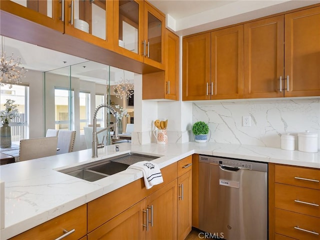 kitchen featuring light stone countertops, decorative backsplash, dishwasher, and sink