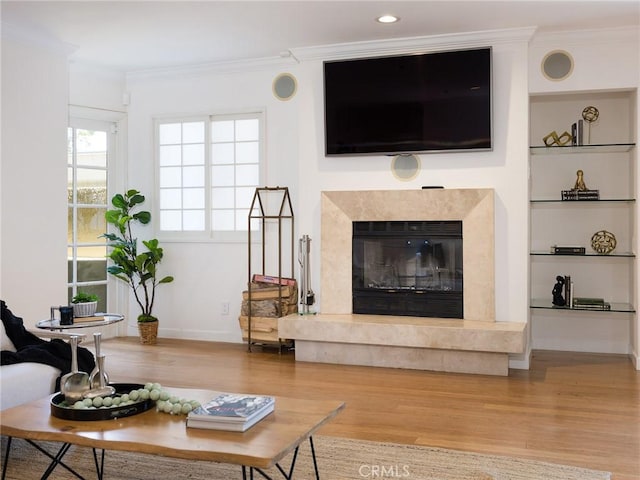 living room with a premium fireplace, crown molding, and hardwood / wood-style flooring