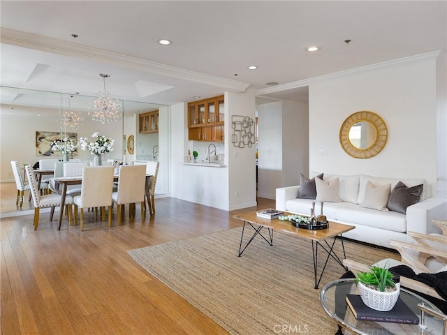 living room featuring sink, ornamental molding, and hardwood / wood-style floors