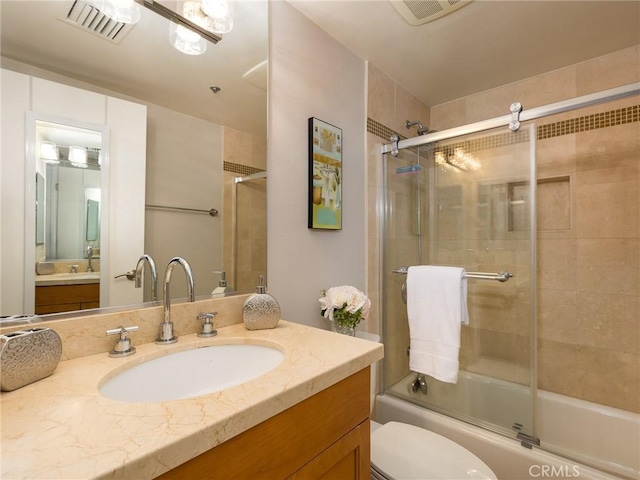 full bathroom featuring toilet, bath / shower combo with glass door, and vanity