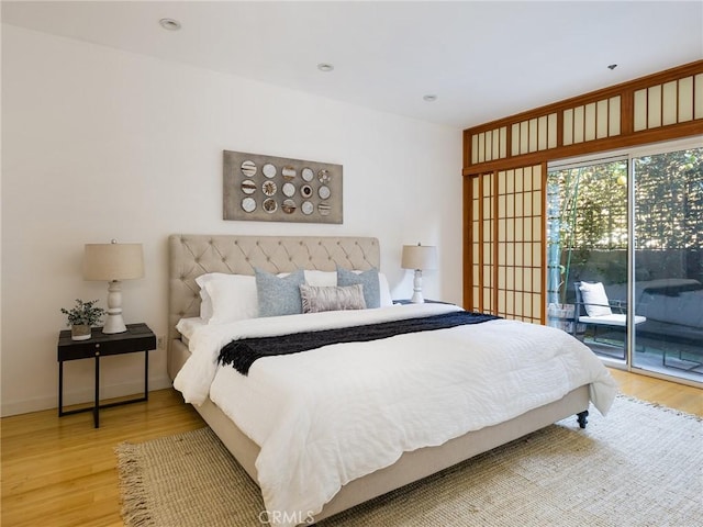 bedroom with access to outside and hardwood / wood-style flooring