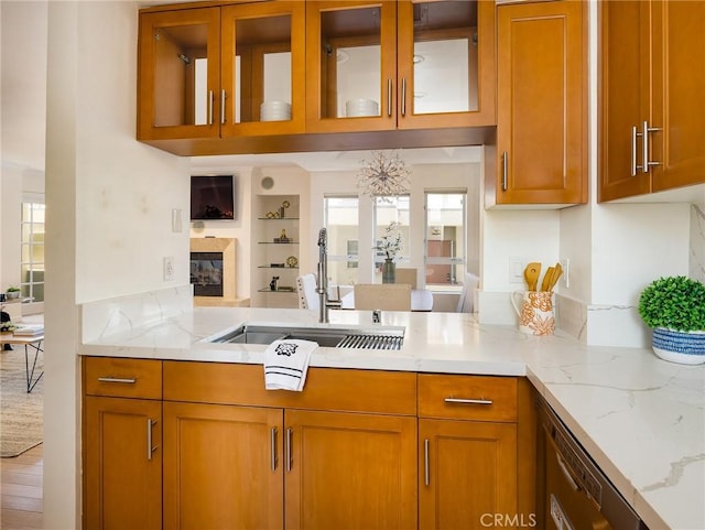 kitchen featuring light stone countertops, dishwasher, and sink