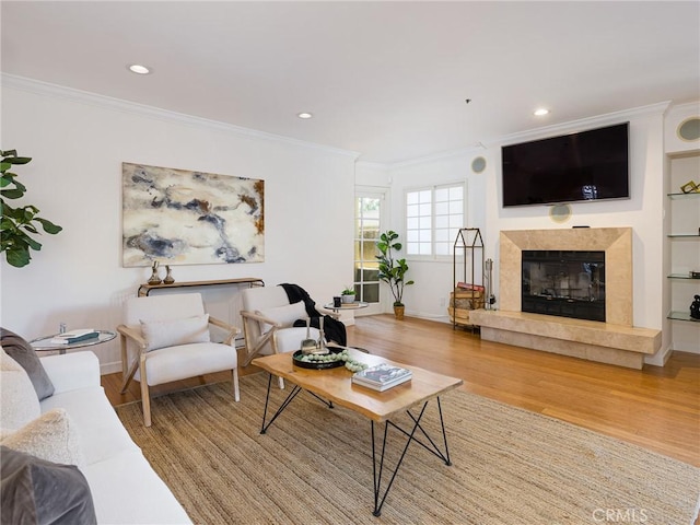 living room featuring a tiled fireplace, ornamental molding, and hardwood / wood-style flooring