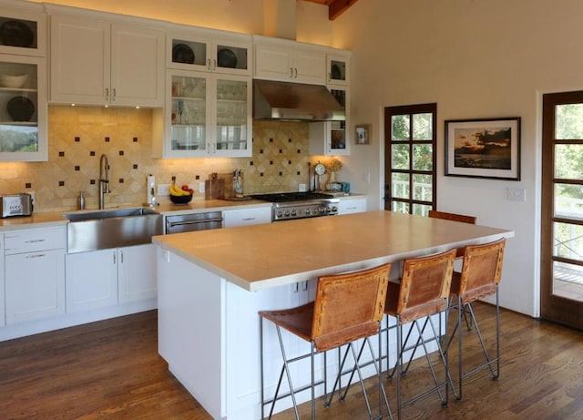 kitchen featuring a kitchen island, a kitchen bar, white cabinetry, sink, and dark hardwood / wood-style floors