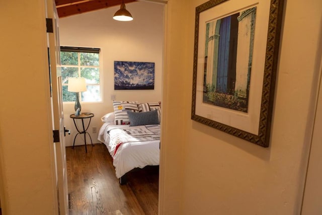 bedroom with lofted ceiling with beams and wood-type flooring