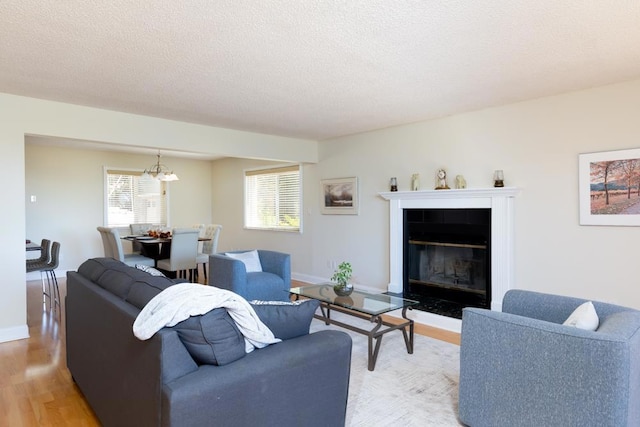 living room with hardwood / wood-style floors, a textured ceiling, a notable chandelier, and a fireplace