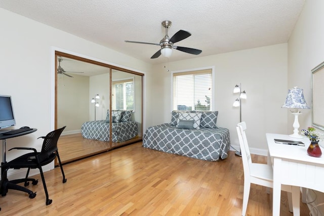 bedroom featuring ceiling fan, wood-type flooring, a closet, and a textured ceiling