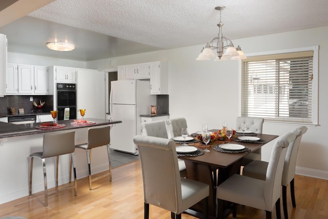 dining room featuring a textured ceiling, light hardwood / wood-style flooring, and a notable chandelier