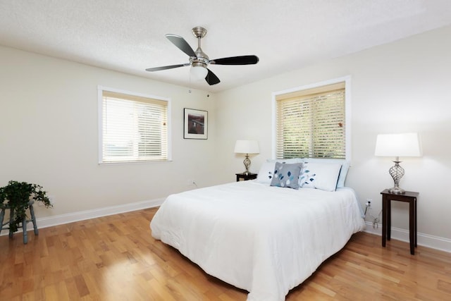 bedroom featuring ceiling fan, light hardwood / wood-style flooring, and multiple windows