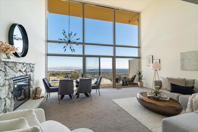 living room featuring a wall of windows, carpet flooring, a fireplace, and a high ceiling