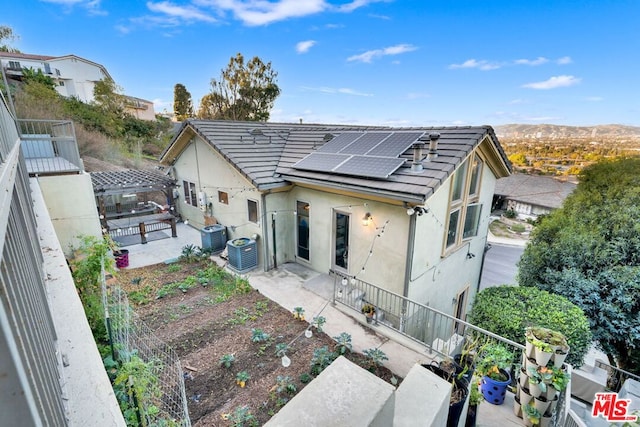 rear view of property featuring a mountain view, solar panels, and central AC