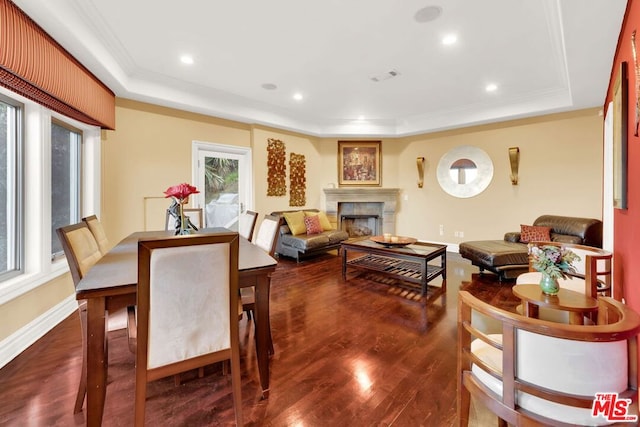 dining room featuring dark wood-type flooring, a tray ceiling, and ornamental molding