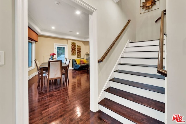 stairway featuring hardwood / wood-style floors, crown molding, and a fireplace