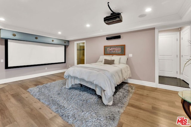 bedroom with wood-type flooring, crown molding, and connected bathroom