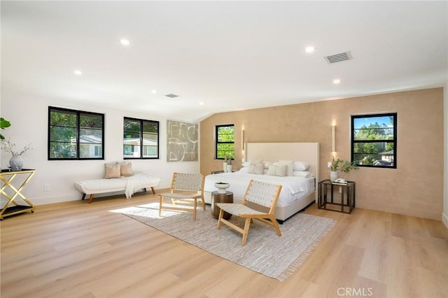 bedroom featuring lofted ceiling, multiple windows, and light hardwood / wood-style flooring