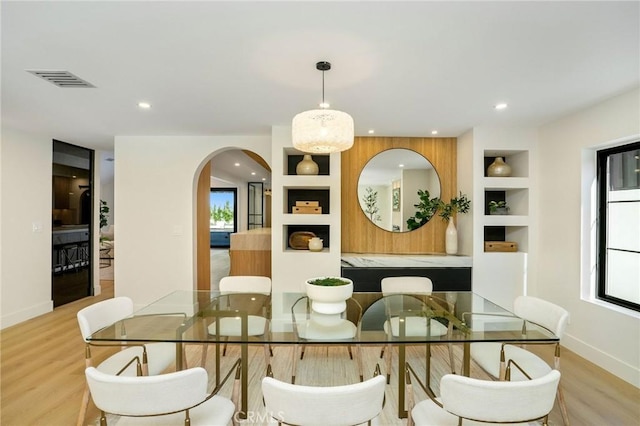 dining area with light hardwood / wood-style floors, plenty of natural light, and built in shelves