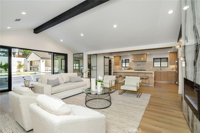 living room with light wood-type flooring, sink, high vaulted ceiling, and beamed ceiling