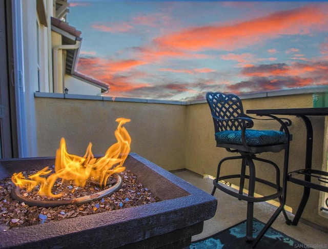 balcony at dusk featuring a fire pit