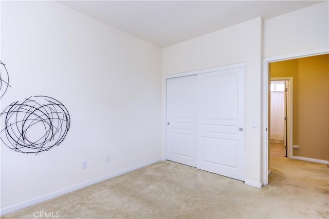 unfurnished bedroom featuring light carpet and a closet