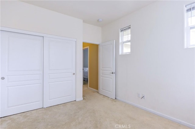 unfurnished bedroom featuring light colored carpet and a closet