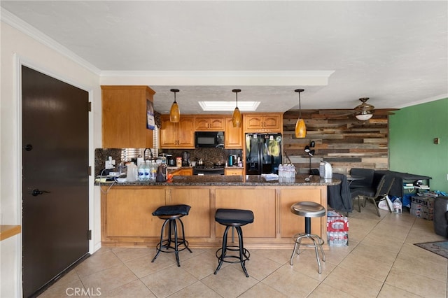 kitchen featuring decorative light fixtures, crown molding, black appliances, and kitchen peninsula